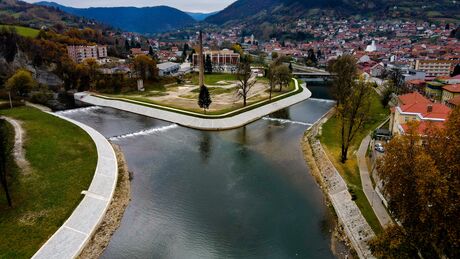 River with two bridges in a city surrounded by buildings and hills in the background