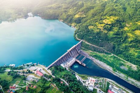 Aerial view of a dam with adjacent reservoir and surrounding forested landscape