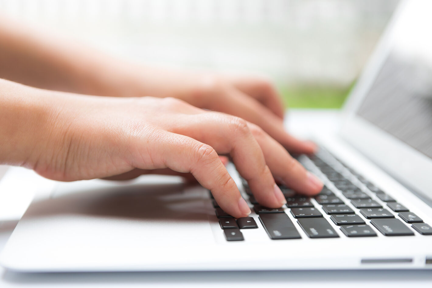Hände tippen auf einer Laptop-Tastatur