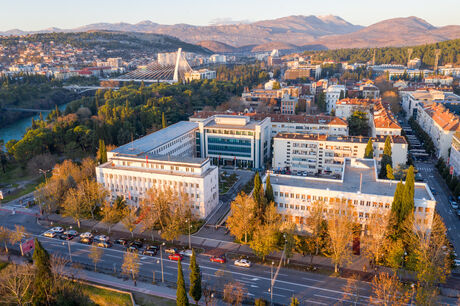 Podgorica Montenegro in autumn: President and Parliament buildings, white in the first row, and Government in the grey one behind. Yellow foliage on the main street in the afternoon, close to sunset