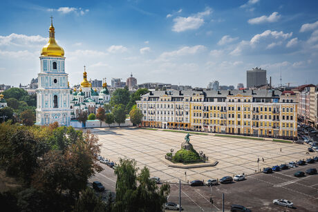 City view with a square surrounded by multi-story buildings and a church with a golden dome