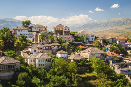 Mountain village with traditional houses and shingle roofs amid wooded hills and mountains under a blue sky with clouds